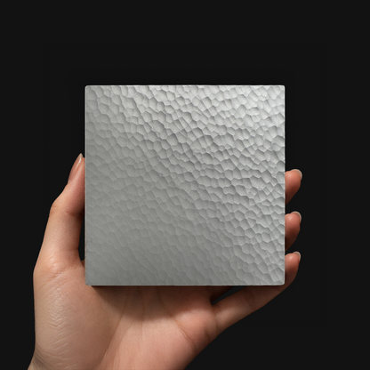 Hand holding a VORONOI aluminum coaster with a cellular texture