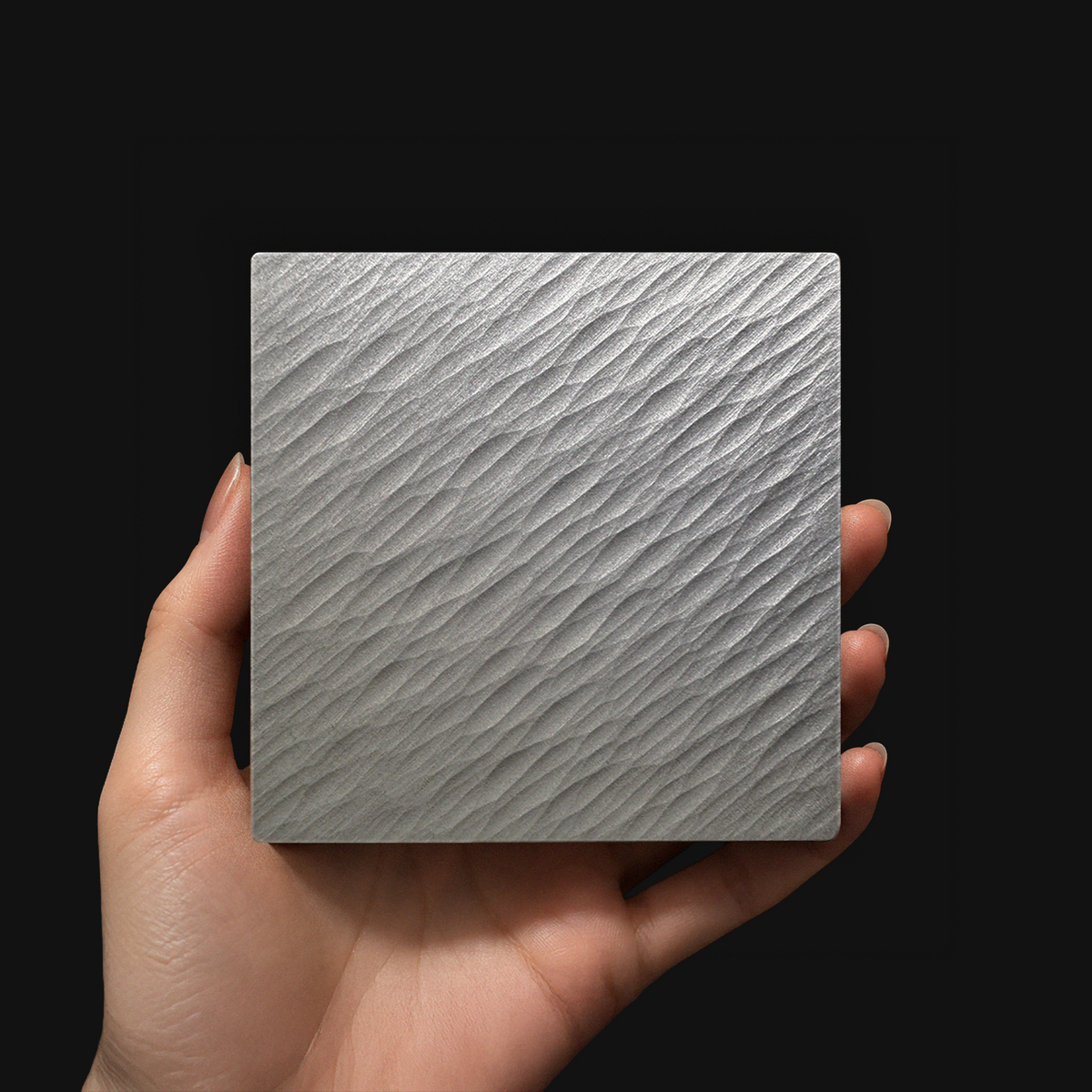 Hand holding a DRIFT aluminum coaster with directional grooves