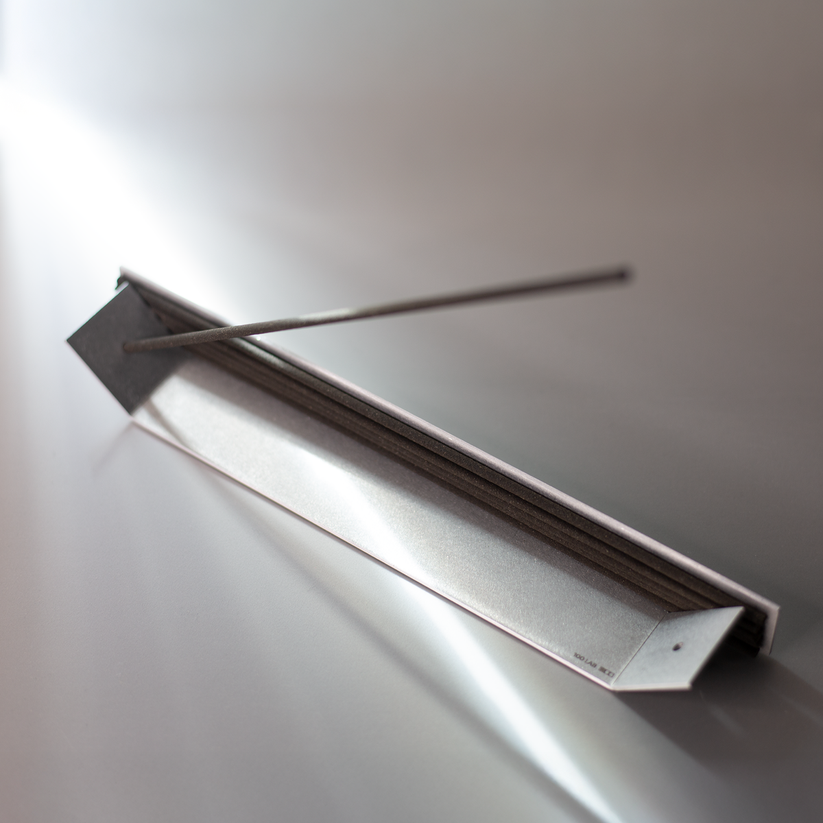 Angled close-up of the aluminum incense holder with stored sticks and ash tray