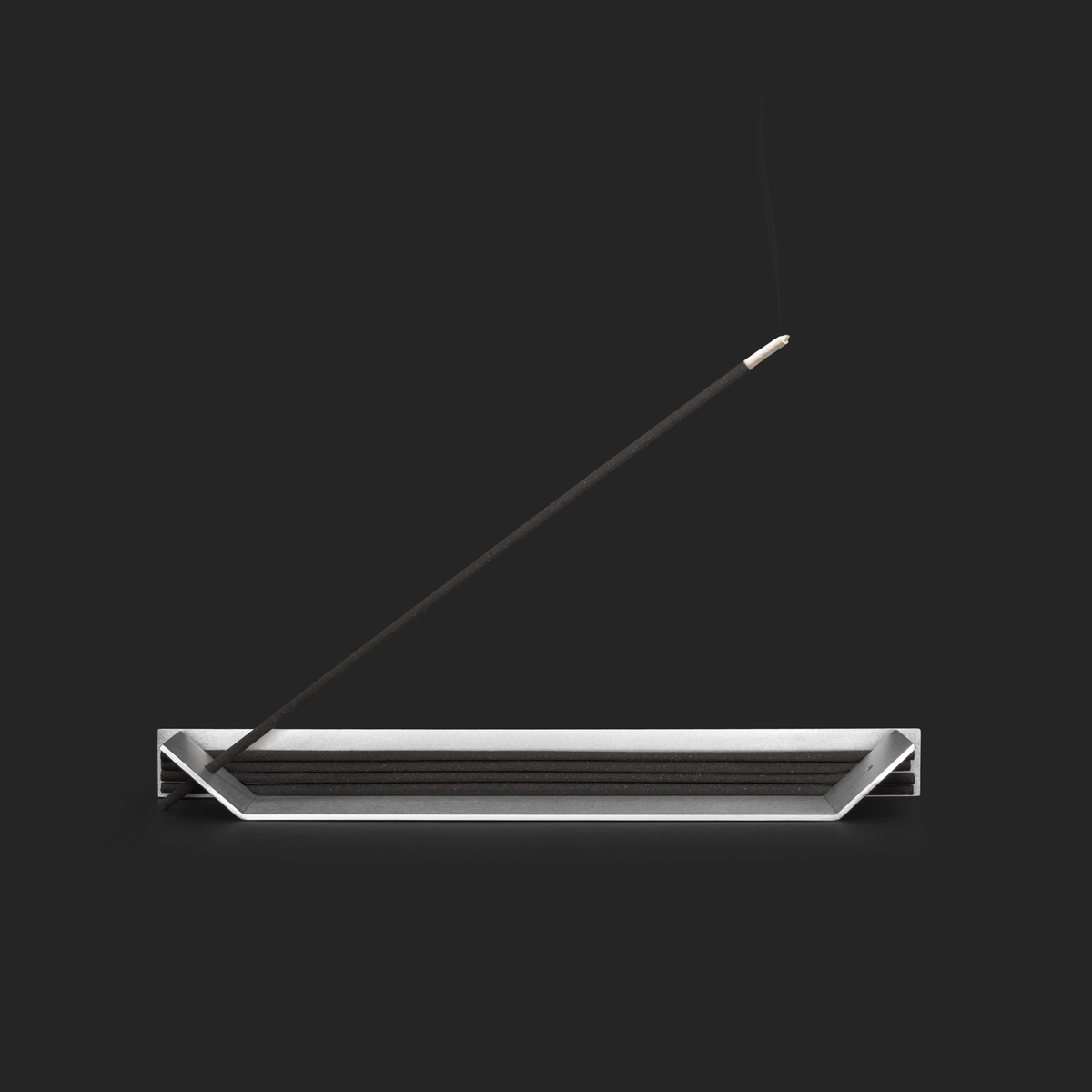 Folded aluminum incense holder with stacked sticks and one burning stick