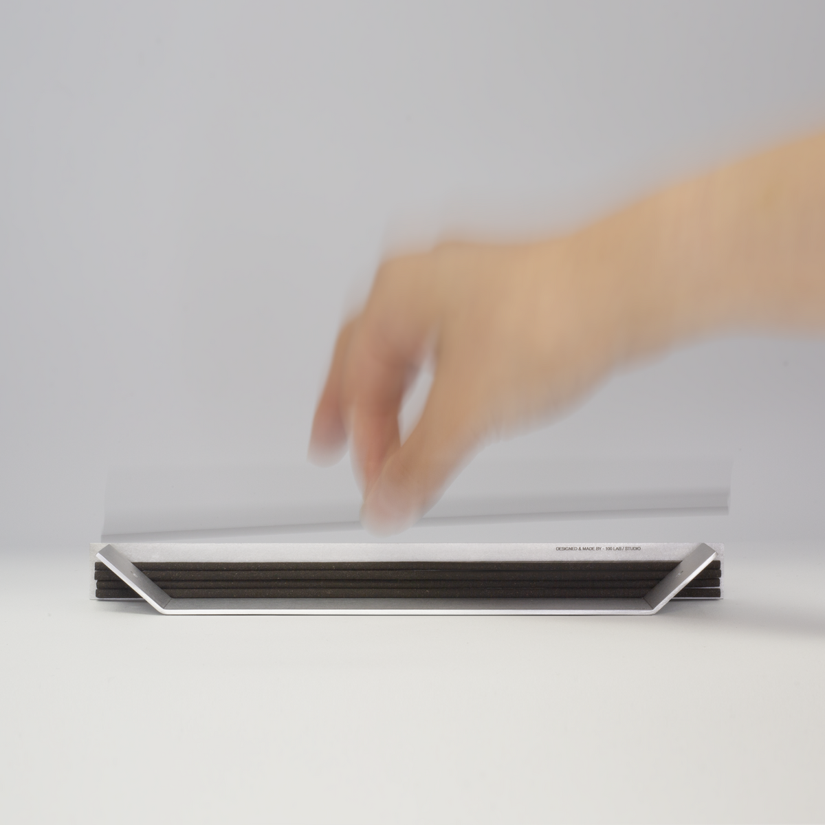 Hand reaching for incense sticks stacked in the aluminum holder